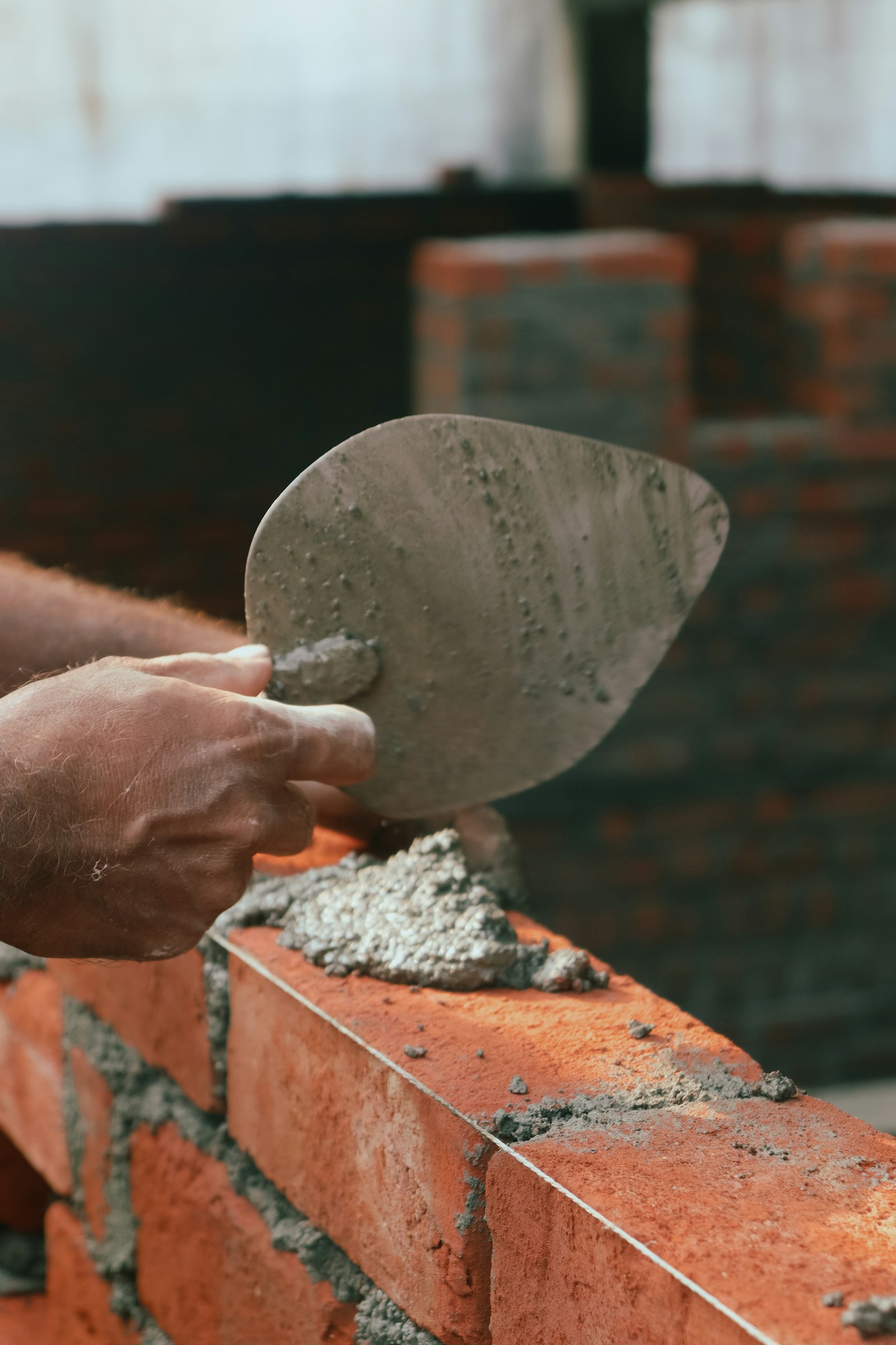 Bricklayer carefully placing a brick on a half-built garden wall